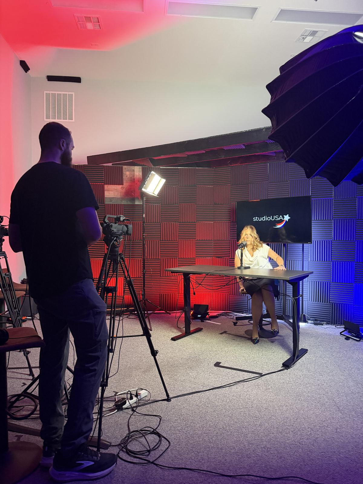 Camera operator framing a guest on the studioUSA set at studioUSA West in Colleyville