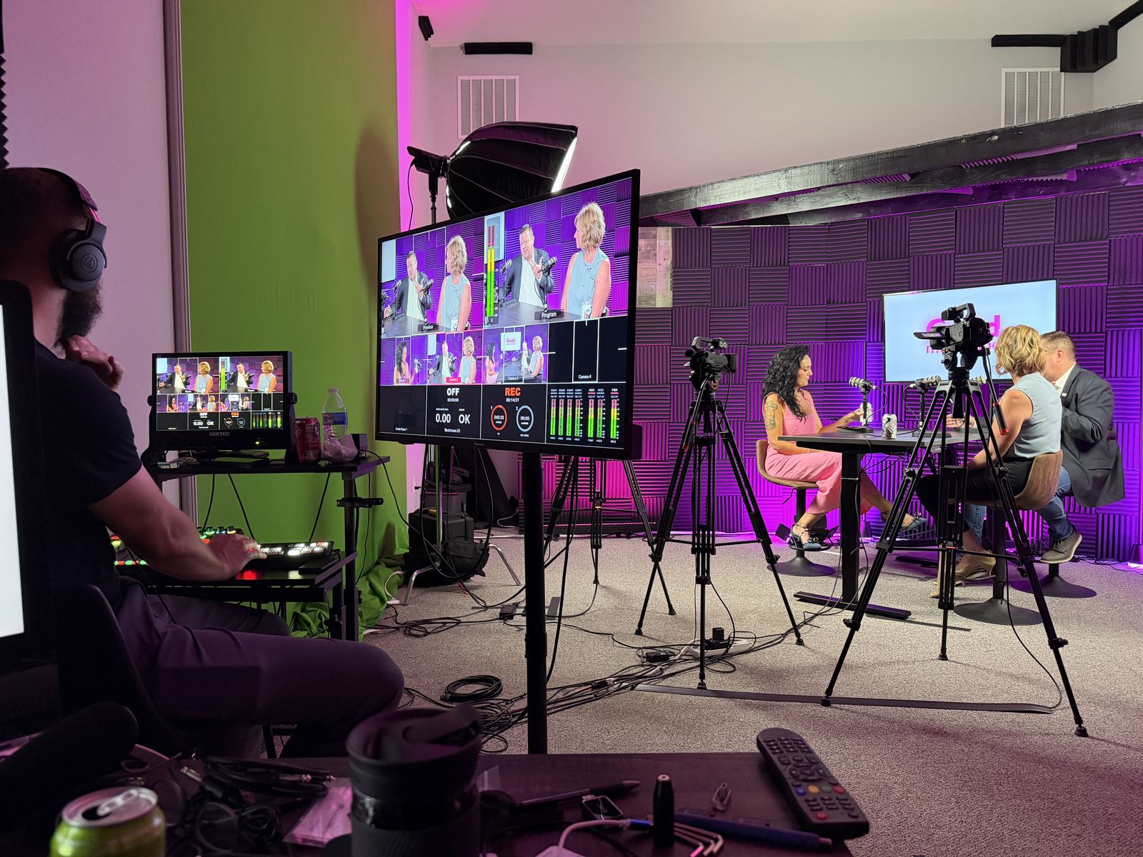 Producer at the switcher watching a multi-camera program feed while two guests record at studioUSA West in Colleyville, Texas